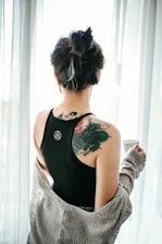 woman in black tank top with green floral tattoo on her back