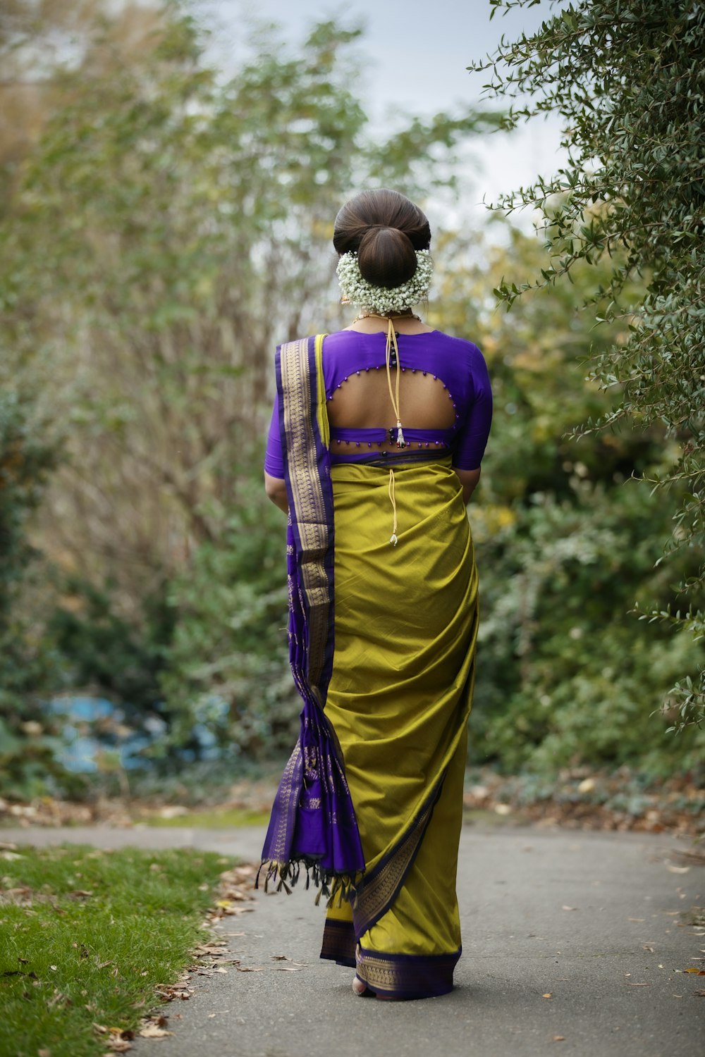 woman in yellow and purple sari standing on road during daytime