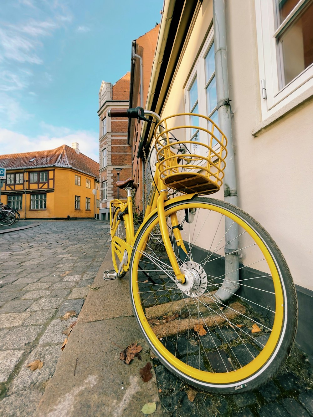 vélo jaune s’appuyant sur un mur de briques brunes pendant la journée