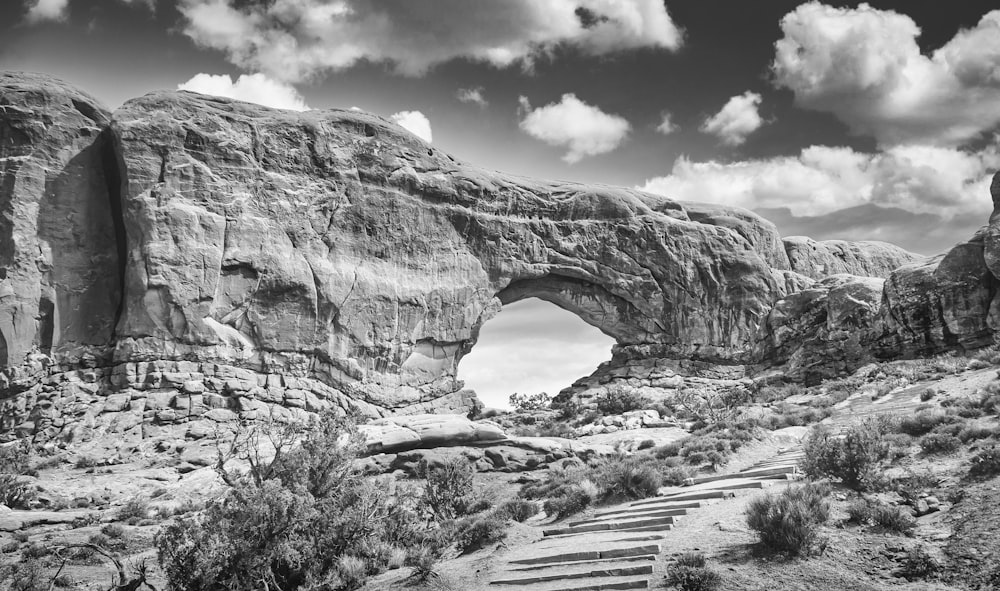 grayscale photo of rock formation under cloudy sky