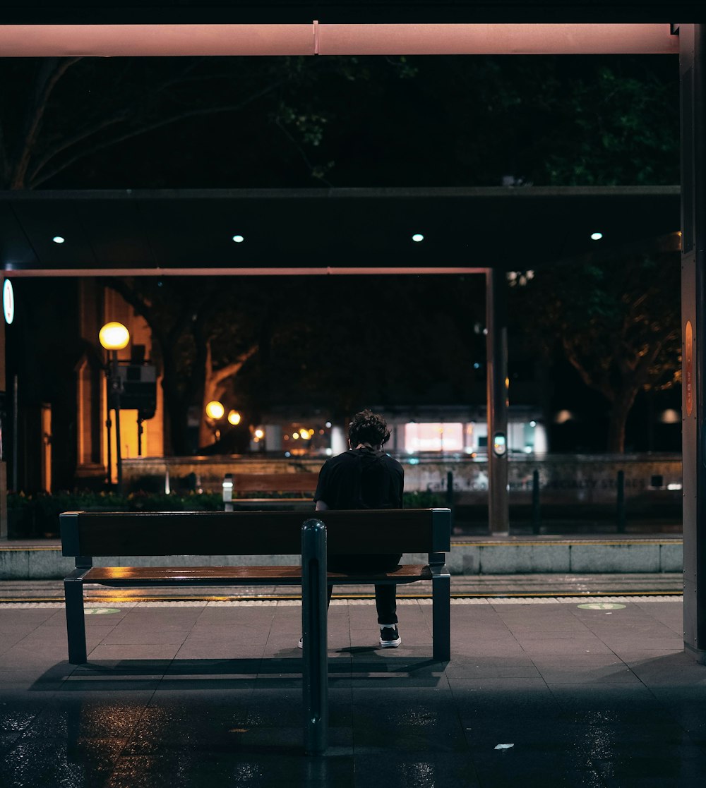man sitting on bench during night time