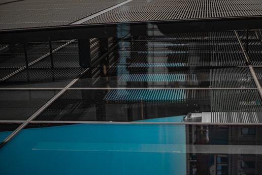 A complex construction of steel beams and glass panels, reflecting light and sky. The architectural structure appears modern and industrial, with a grid-like pattern.