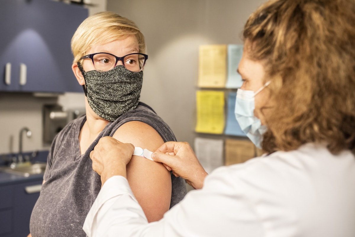 vacunas del coronavirus, woman in white shirt covering face with black knit cap