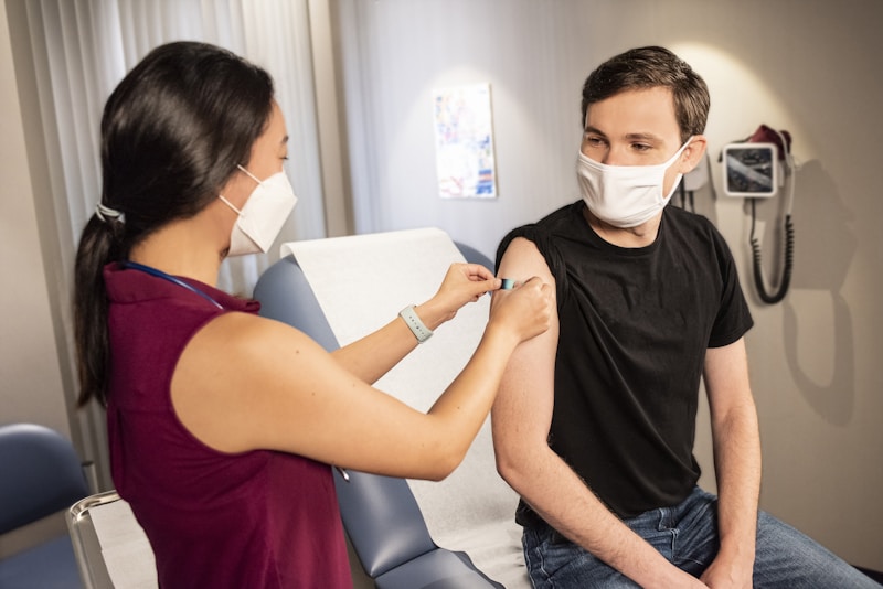 vacunas del coronavirus, woman in black tank top and white face mask sitting beside woman in maroon sleeveless shirt