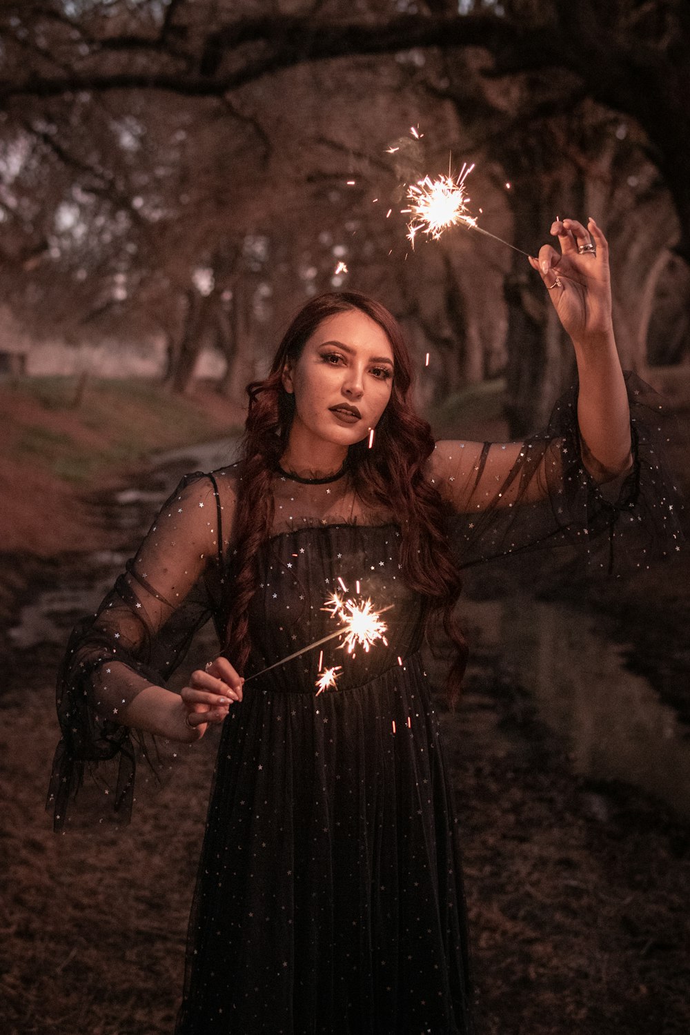 woman in black spaghetti strap dress holding sparkler