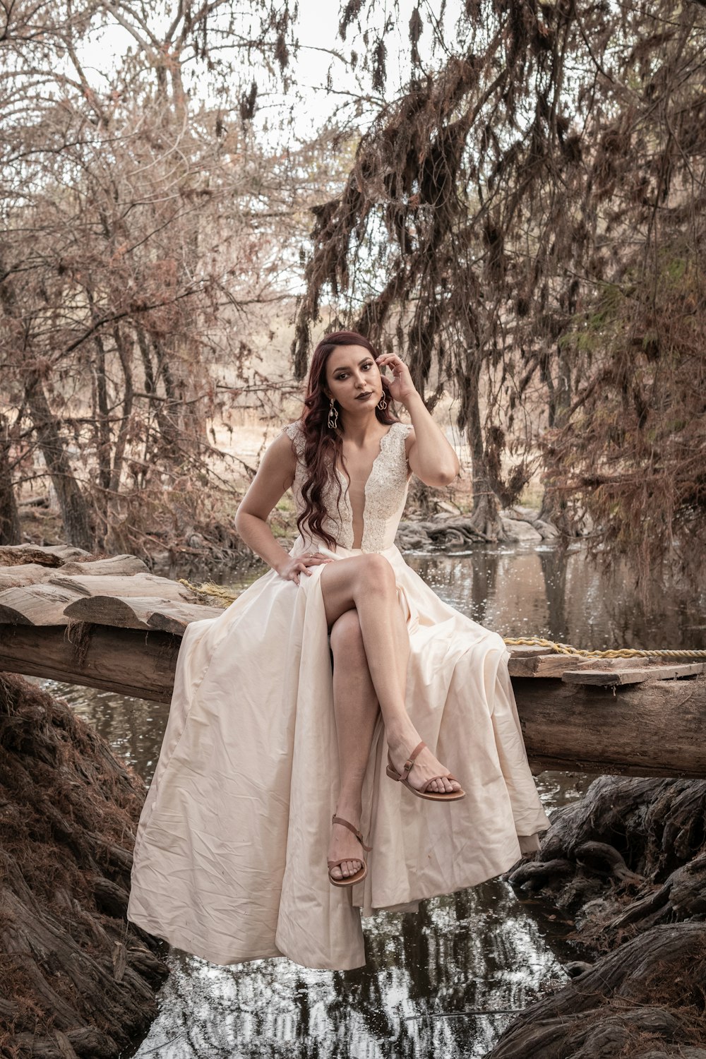 woman in white sleeveless dress sitting on brown tree branch during daytime