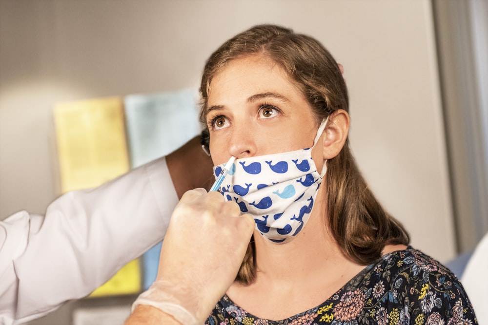 woman in white and black floral scoop neck shirt covering her face with blue and white