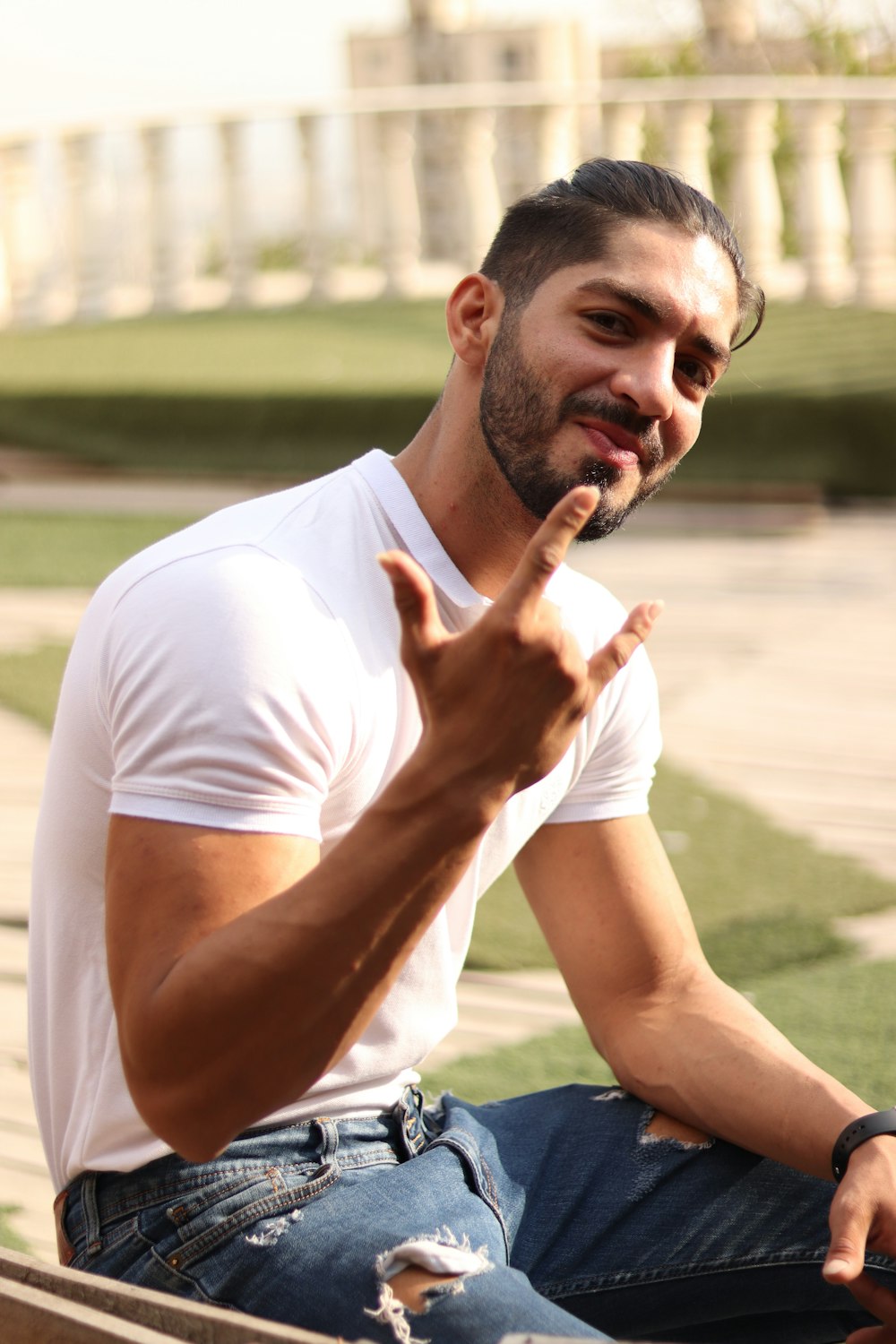 man in white crew neck t-shirt sitting on blue textile during daytime