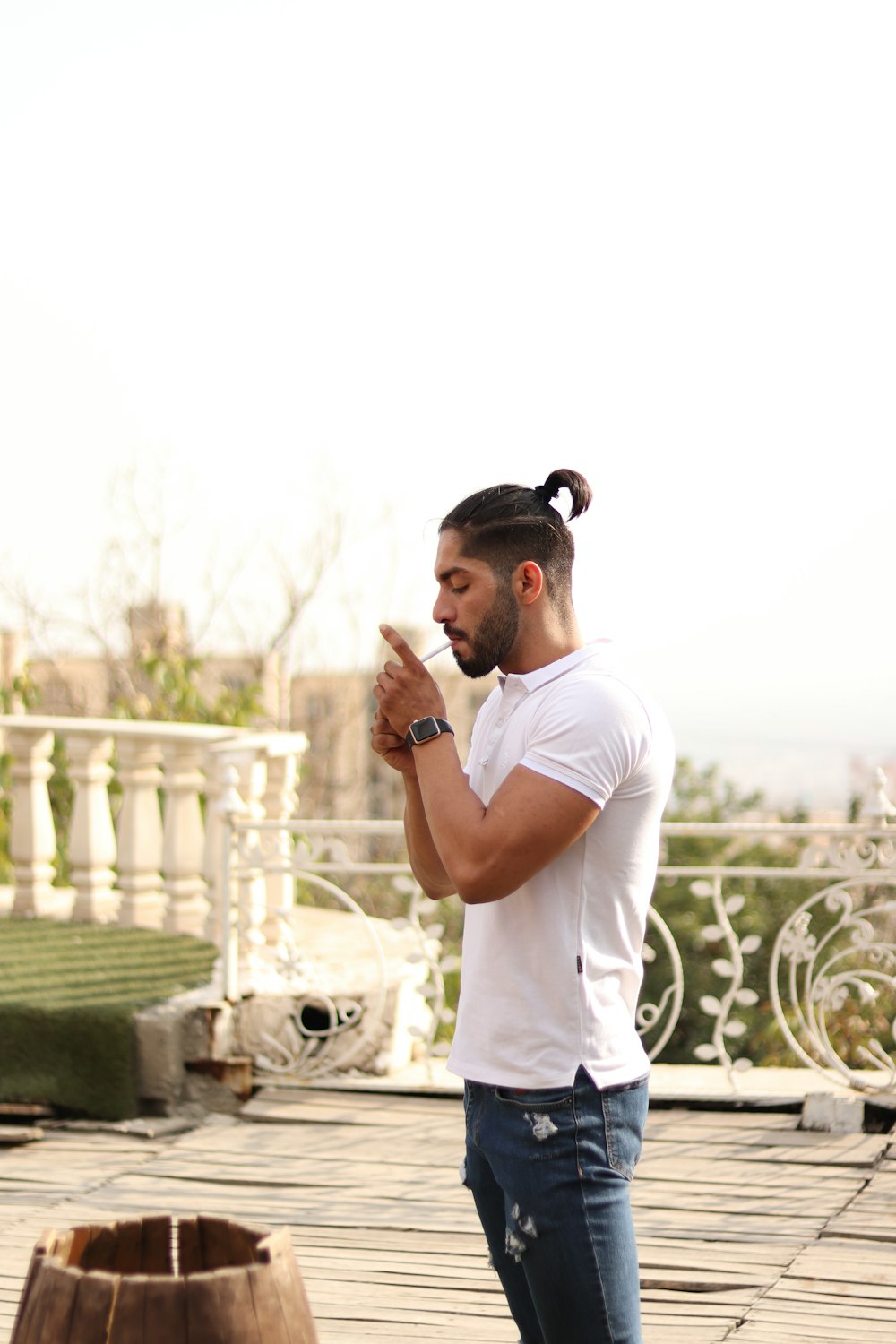 man in white t-shirt and black pants standing near white fence during daytime