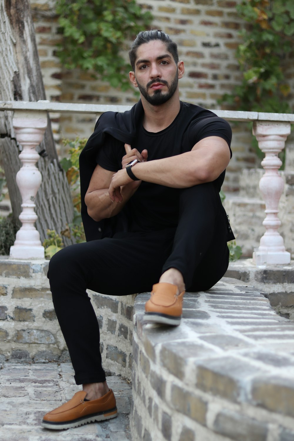 man in black crew neck t-shirt and black pants sitting on concrete bench during daytime