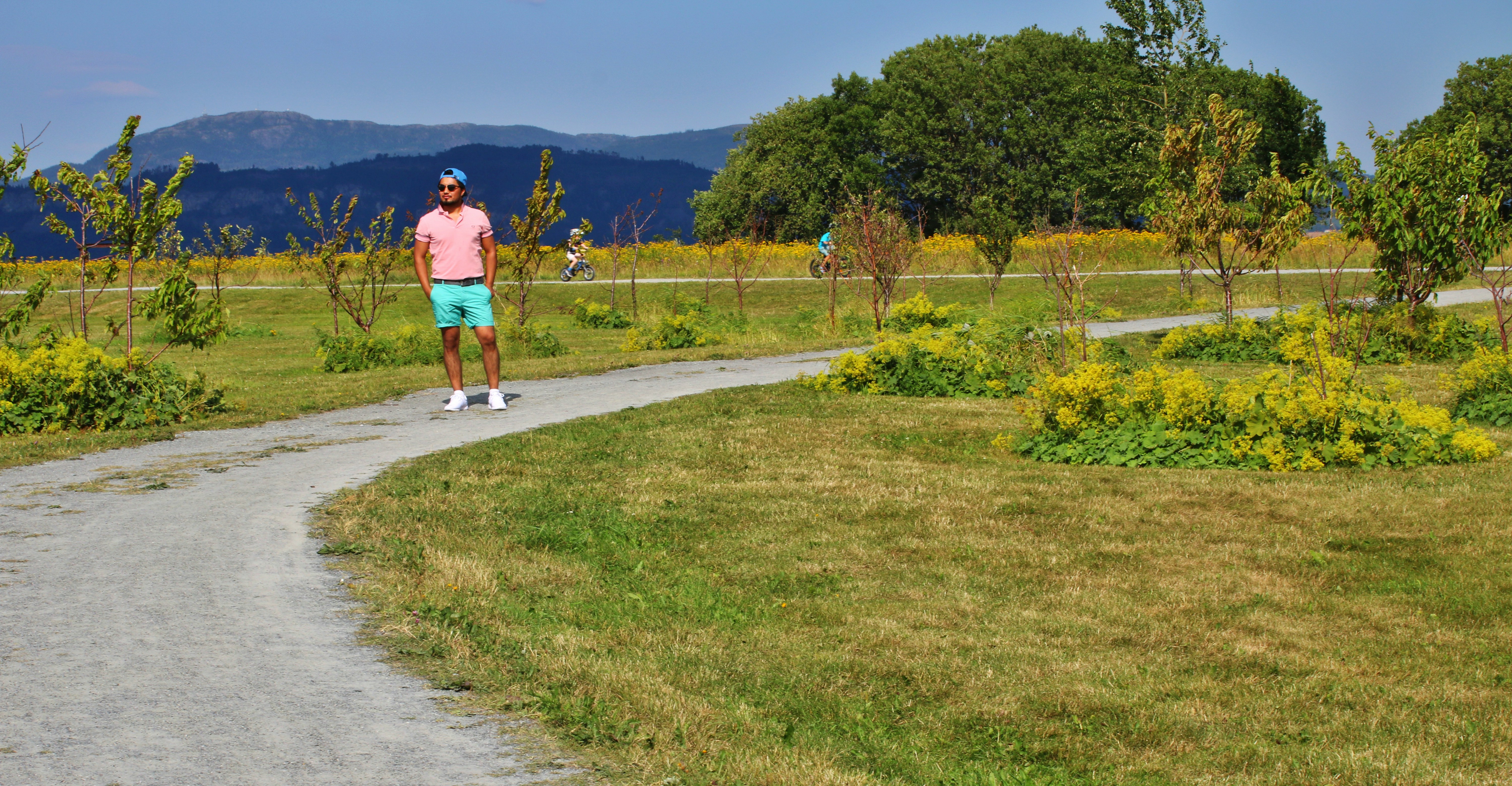 man in orange shirt and blue shorts walking on gray concrete pathway during daytime
