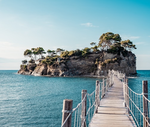 brown wooden bridge over blue sea under blue sky during daytime