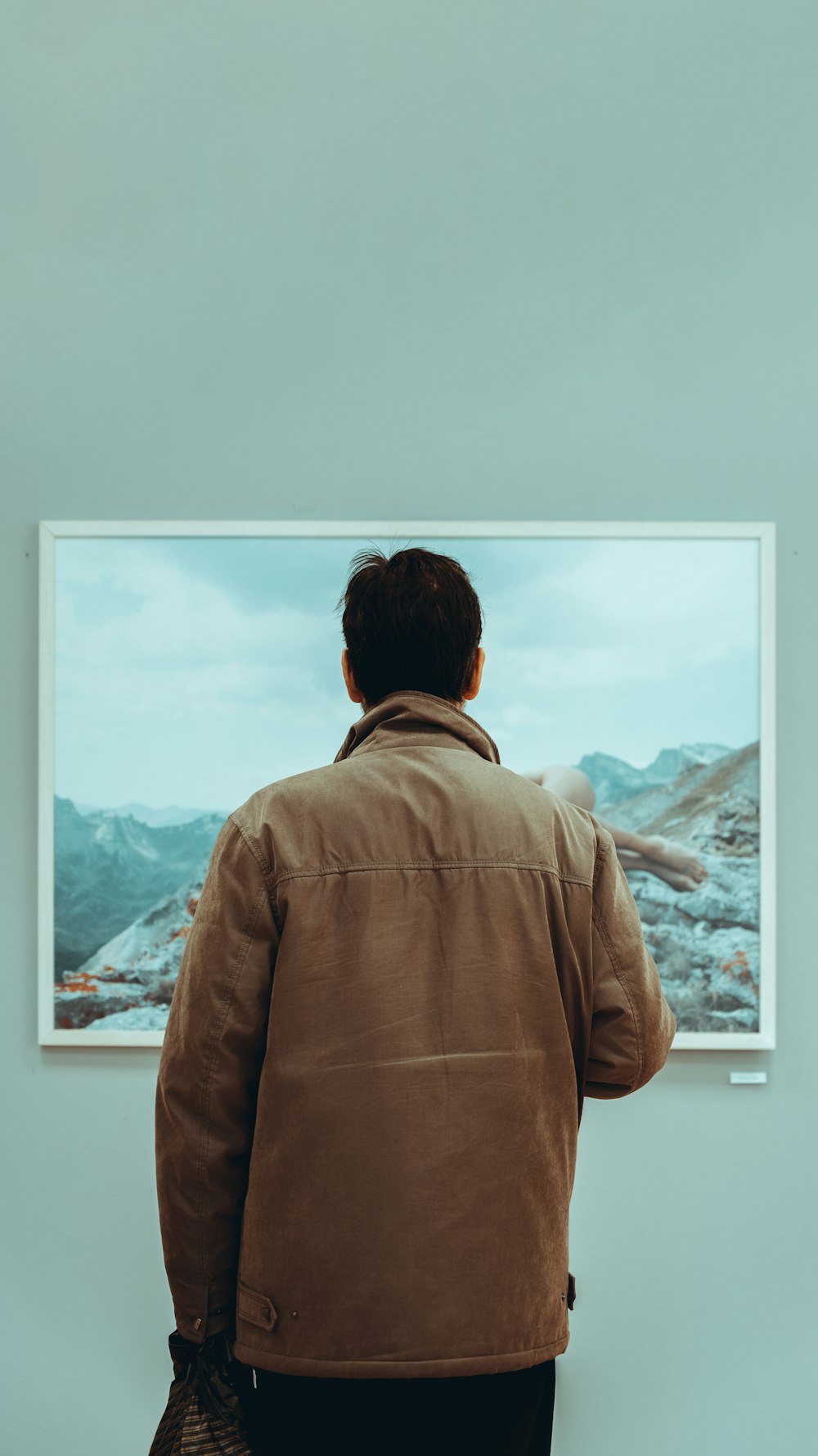 man in brown jacket looking at the mountains during daytime