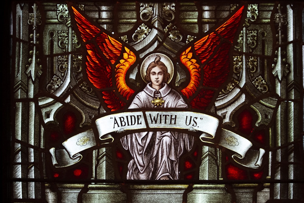 a stained glass window with an angel holding a banner