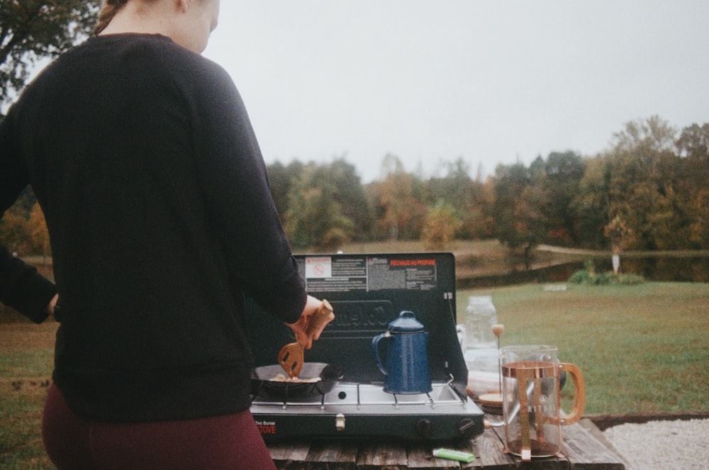 man in black long sleeve shirt standing in front of black and gray outdoor grill during