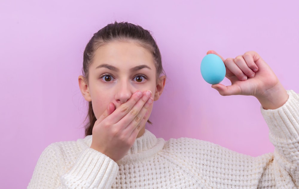 woman in white sweater holding blue balloon