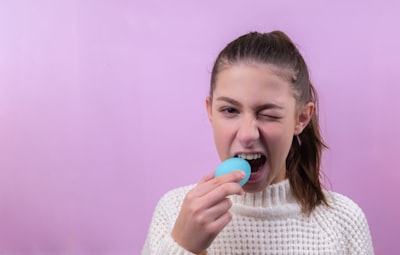 girl in white knit sweater holding red lollipop taste zoom background