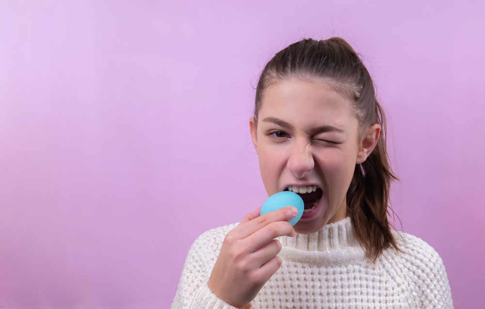 girl in white knit sweater holding red lollipop