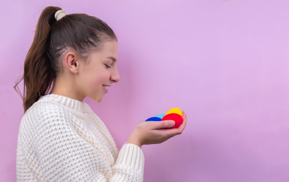 woman in white knit sweater holding blue ball