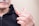 A person holding a set of removable dentures with a few teeth visible, against a blurred background.