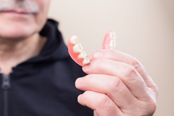 Smiling middle-aged woman showing off her new denture with confidence in a cozy home environment.