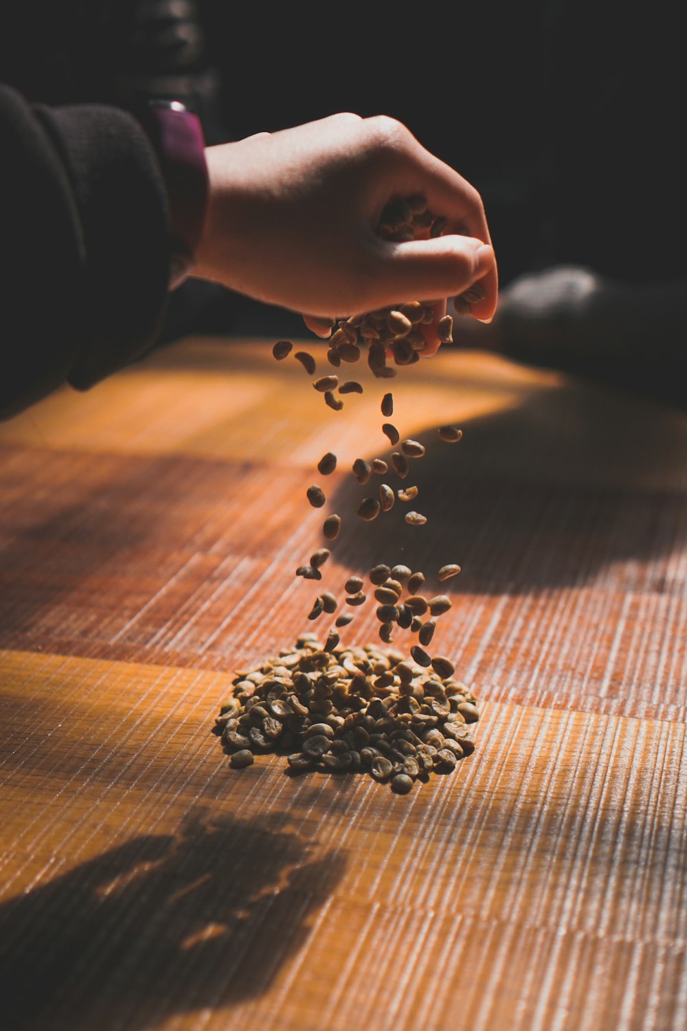 person holding coffee beans on brown wooden table