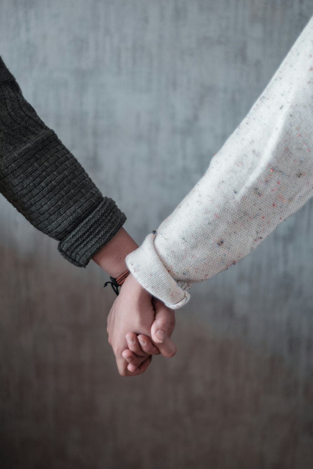 person in black long sleeve shirt holding hands with woman in white long sleeve shirt