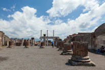 Tourists exploring ancient Zapotec ruins under a bright blue sky.