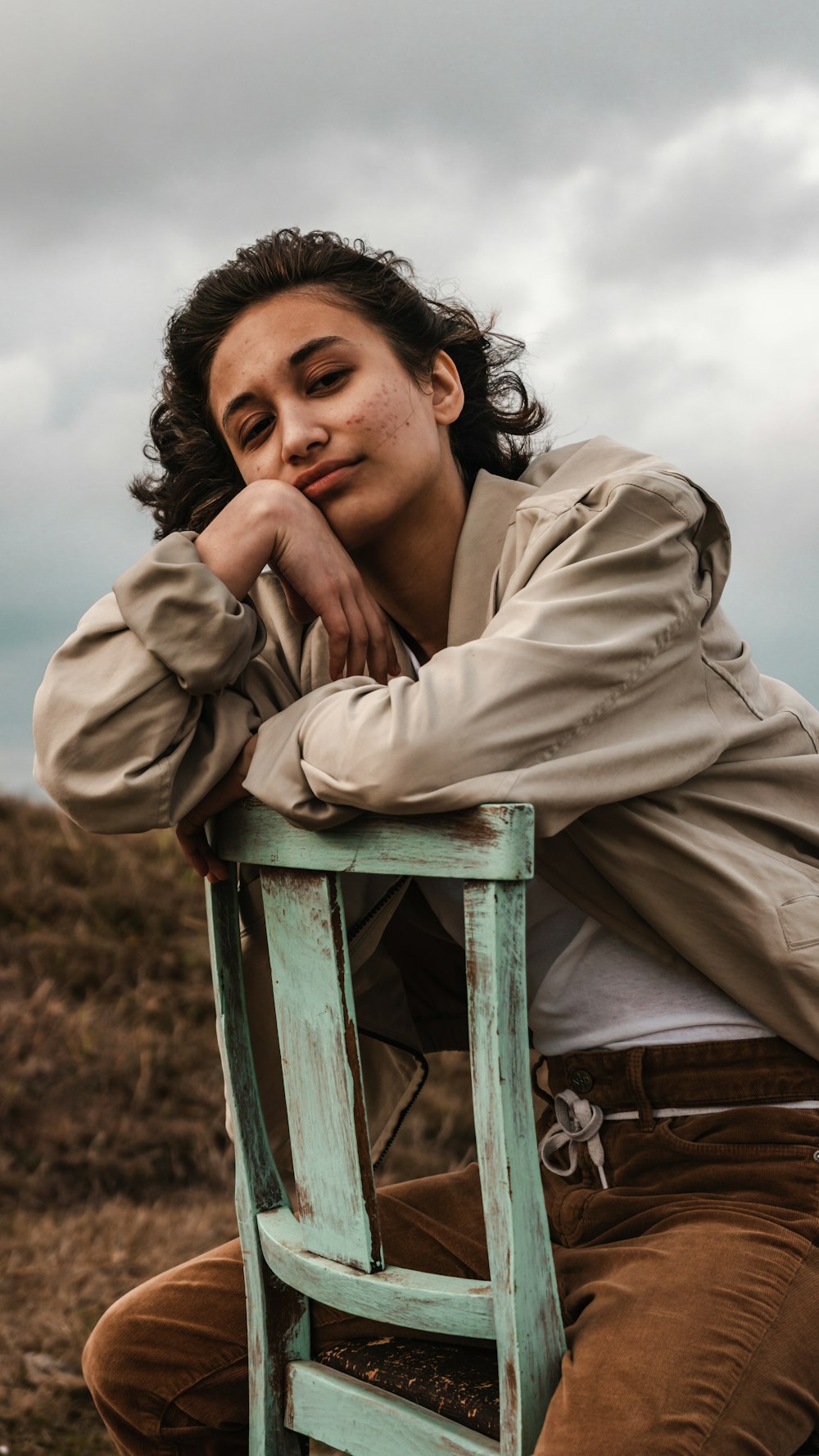 woman in beige coat sitting on green wooden chair