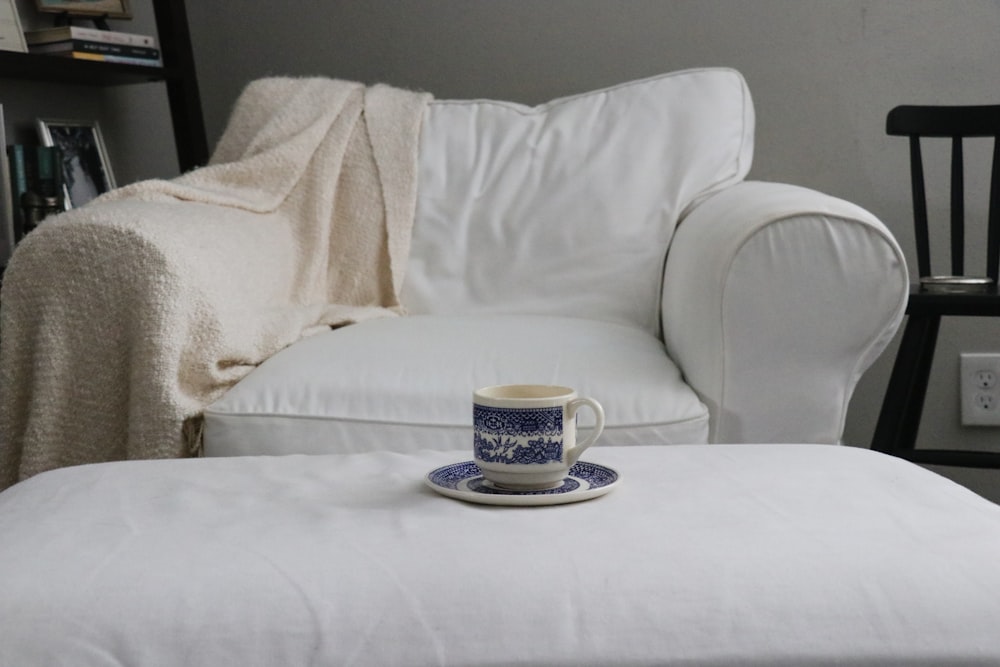 Tasse en céramique blanche et bleue sur soucoupe en céramique blanche