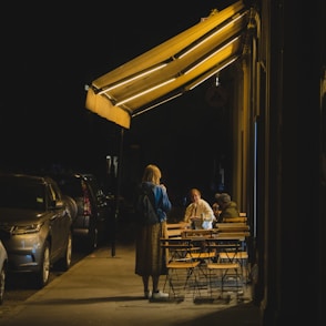 man in blue shirt sitting on brown wooden bench during night time