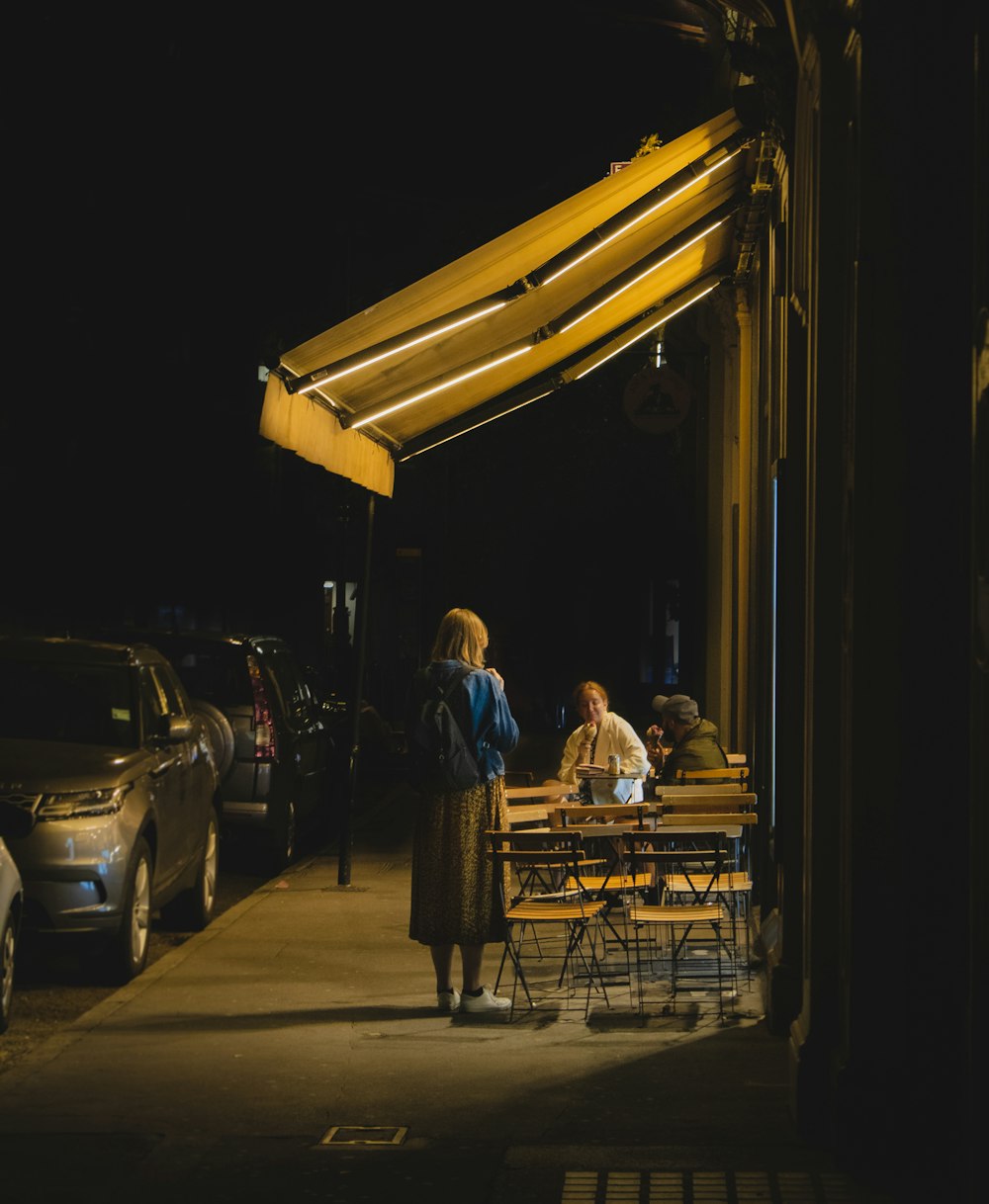 man in blue shirt sitting on brown wooden bench during night time