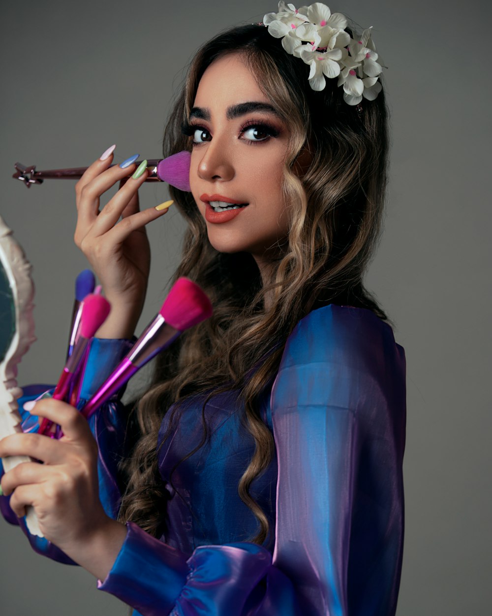 woman in blue long sleeve shirt holding makeup brush