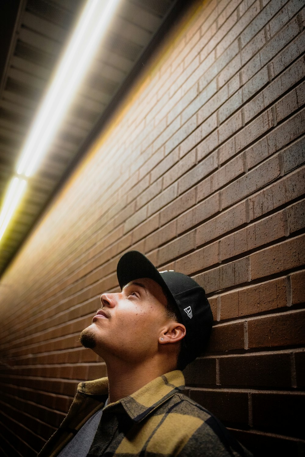 a man standing in front of a brick wall