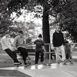 A group of young skaters practicing tricks on a sunny skatepark ramp.