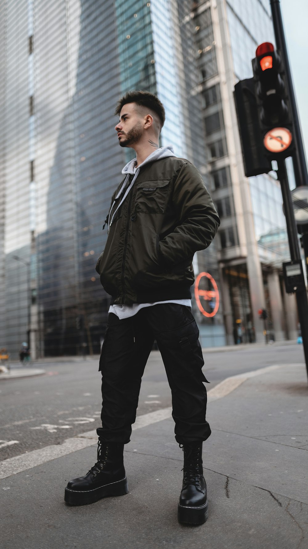 man in black leather jacket and black pants standing on sidewalk during daytime