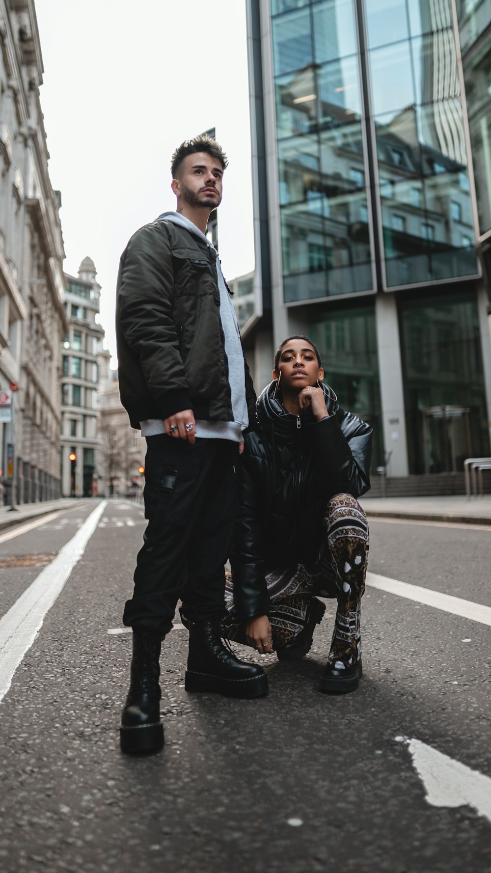 man in black leather jacket and black pants sitting on gray concrete road during daytime