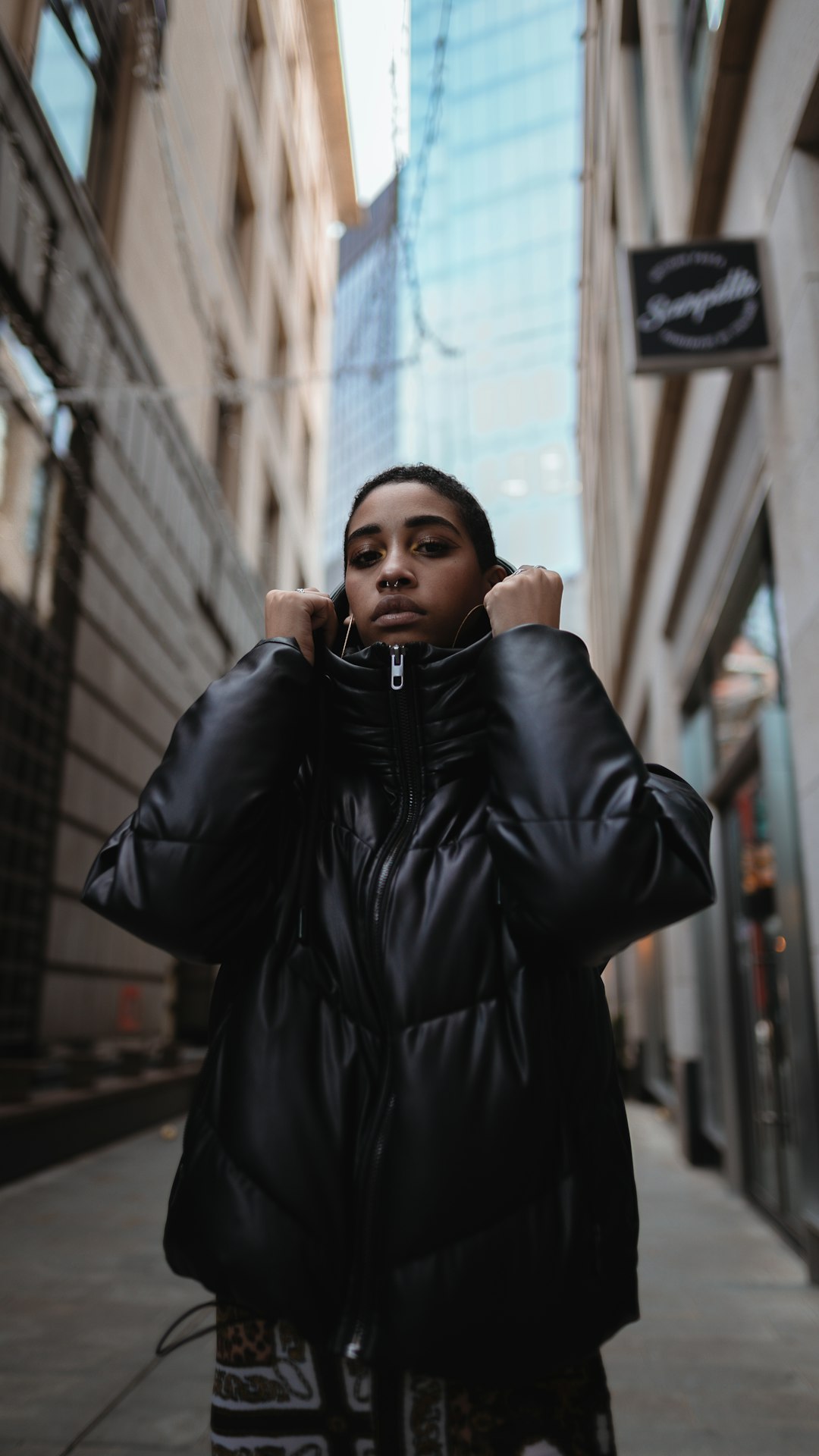 woman in black leather jacket standing near building during daytime