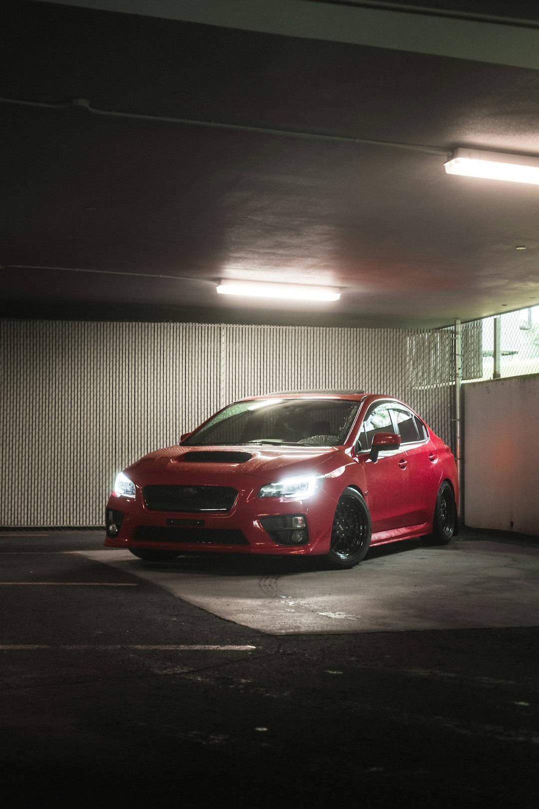 red sedan parked near white wall