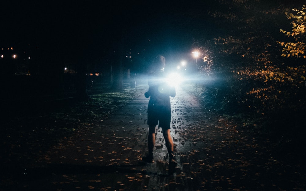 man in black jacket walking on street during night time