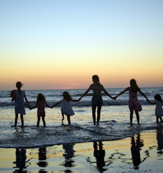a family holding hands on the beach at sunset