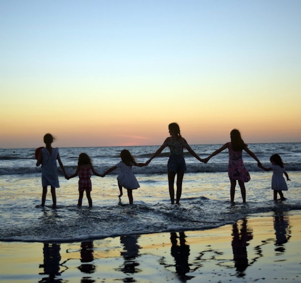 a family holding hands on the beach at sunset