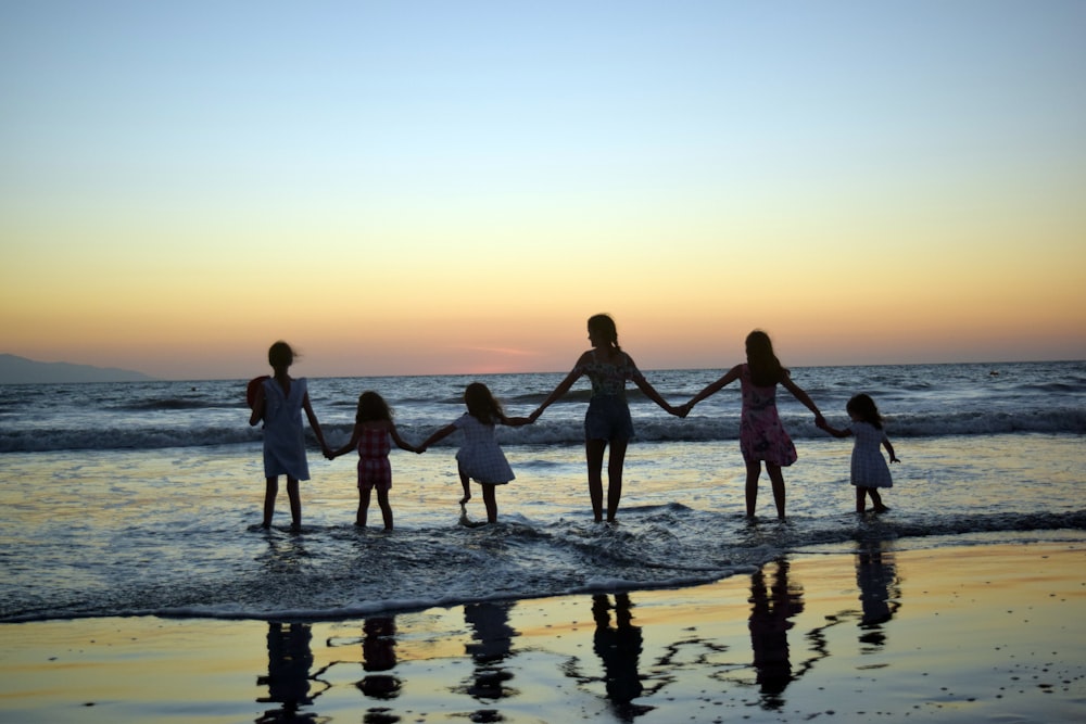 a family holding hands on the beach at sunset