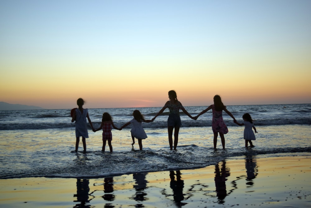 Una familia cogida de la mano en la playa al atardecer