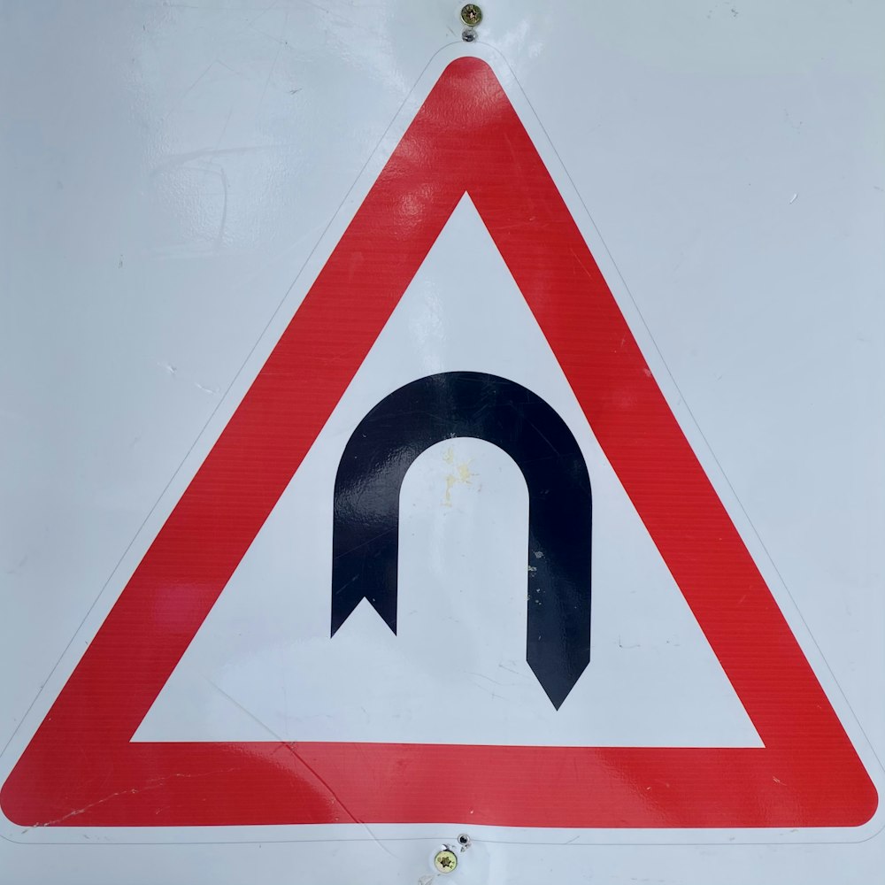 a red and white sign with a black arrow on it
