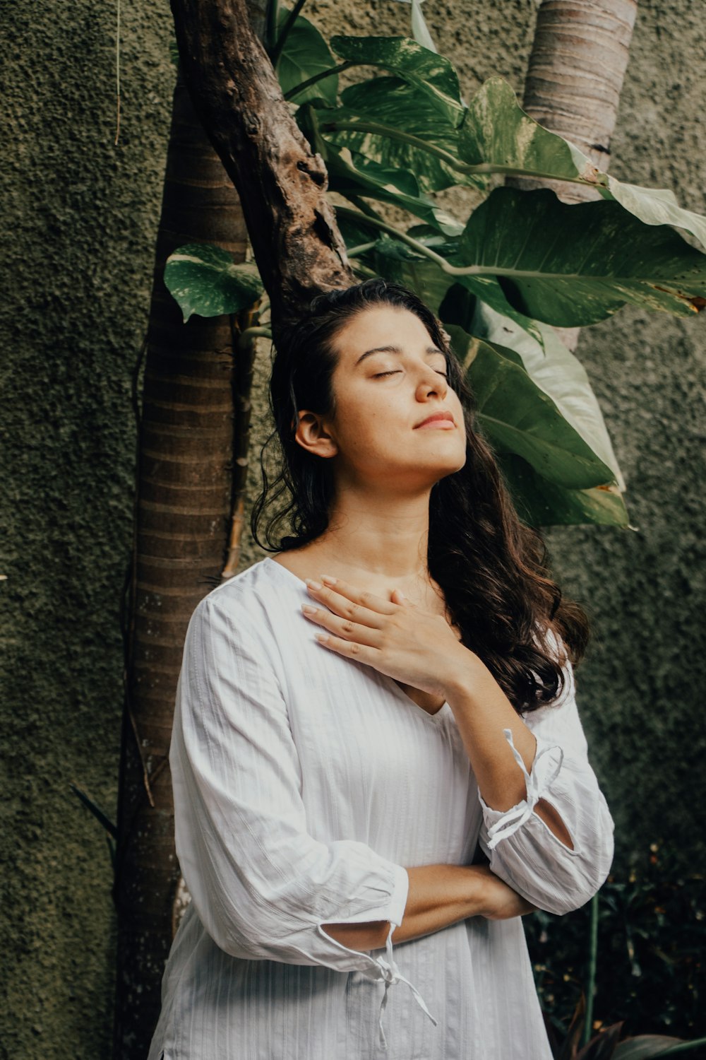 woman in white dress leaning on tree