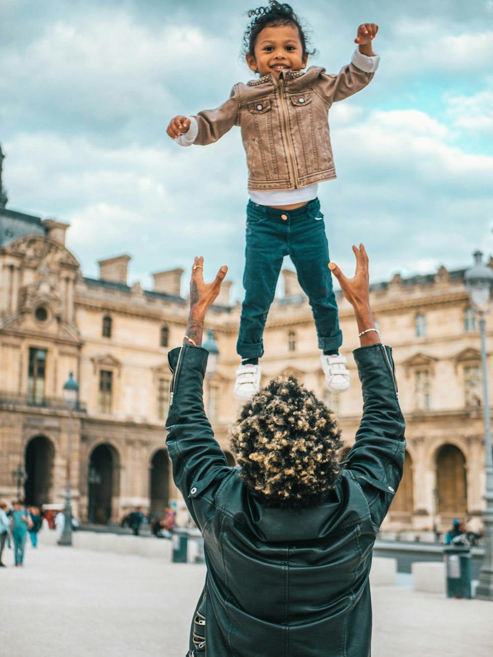 man in brown jacket and blue denim shorts jumping on air during daytime