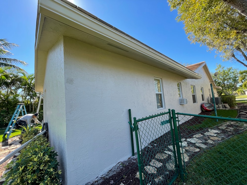 white concrete house with green metal fence