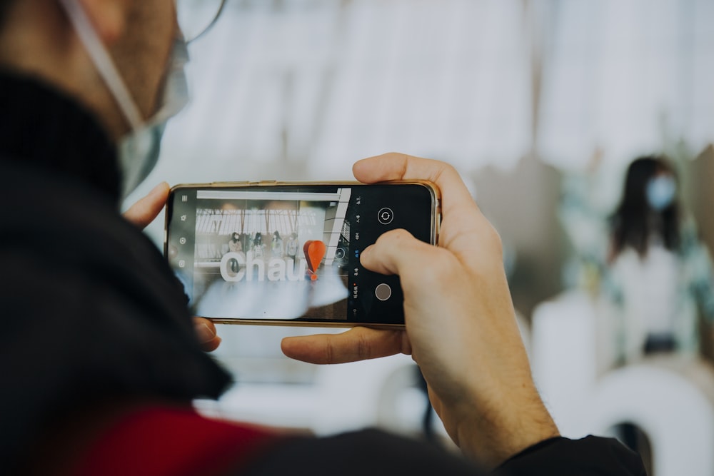 personne tenant un iphone 6 argenté prenant une photo du pont