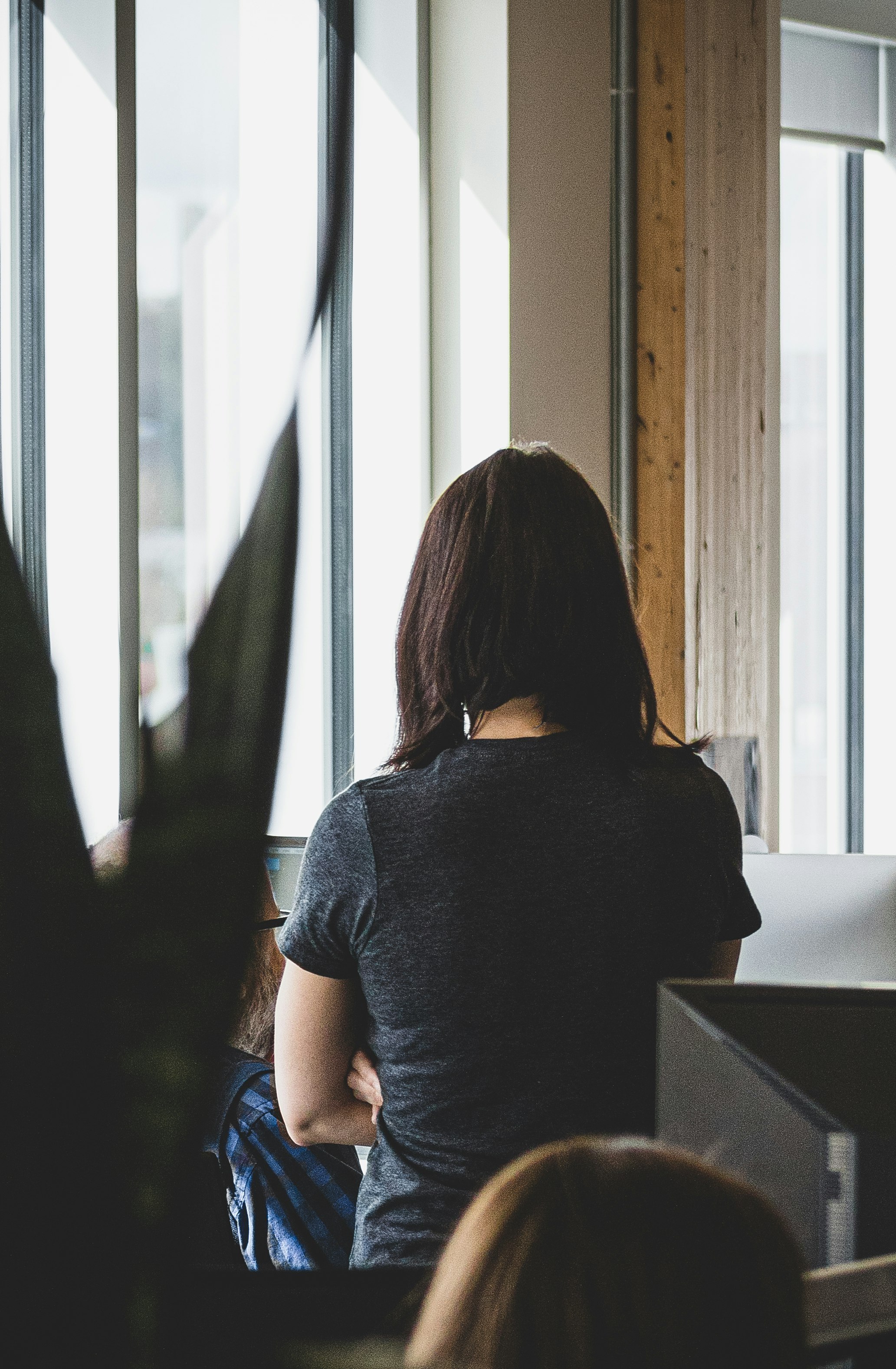 woman in gray shirt standing near window